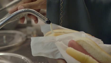 pouring sauce on a hot dog