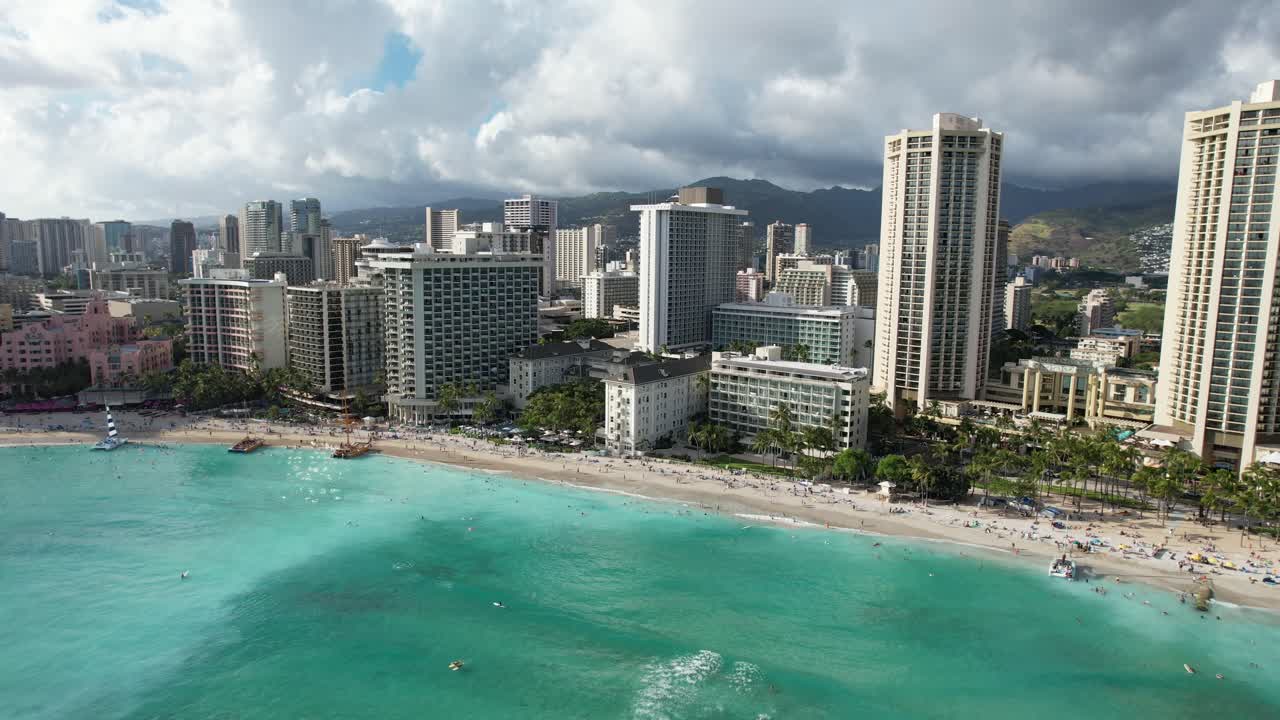 4k riprese aeree con drone rotante di una bellissima destinazione per le vacanze sull'isola rivelano hotel di lusso e famiglie in vacanza che si godono il surf, il sole e la sabbia