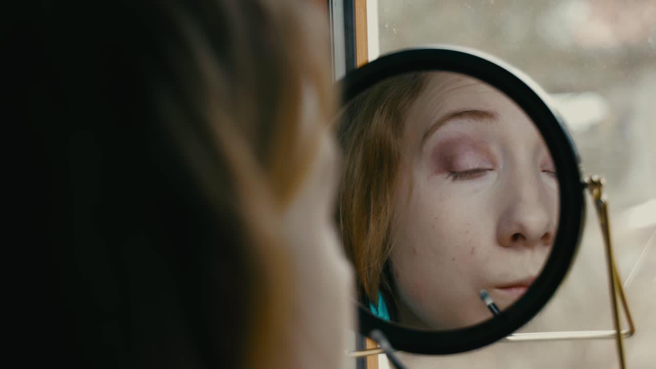 Woman Applying Eye Makeup in Front of a Mirror