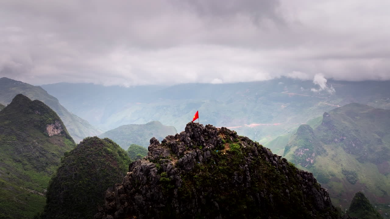 Vietnamese flag waving on mountain peak, sweeping views of lush valleys and rugged landscapes, Aerial forward