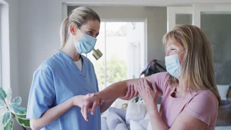 Trabajadora-De-Salud-Estirando-El-Brazo-De-Una-Mujer-Mayor-En-Casa