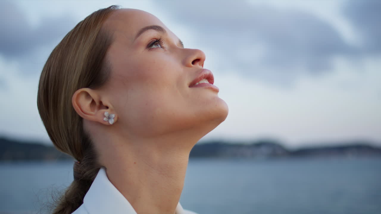 una chica despreocupada respirando el aire de la noche de pie en un terraplén sombrío de cerca.