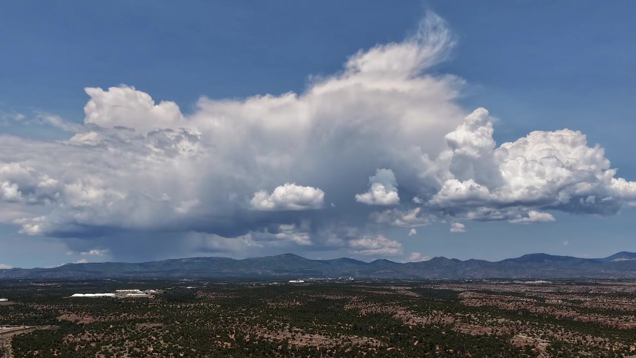Timelapse 4K UHD con drone di nuvole cumulo che si trasformano rapidamente, formandosi sopra un'ampia mesa del sud-ovest. Dinamiche strutture di nuvole bianche si addensano pesantemente sopra il deserto aspro e la lontana cresta montuosa.