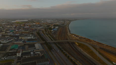 Carretera-Y-Ferrocarril-Que-Conducen-A-Lo-Largo-De-La-Costa-Del-Mar.-Vista-Aérea-De-La-Infraestructura-De-Transporte-En-La-Ciudad-Al-Atardecer.-Puerto-Elisabeth,-Sudáfrica