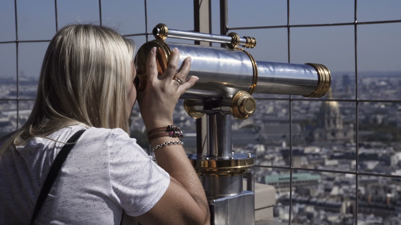 Woman looking through a telescope at the Eiffel Tower in Paris