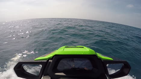 pov of riding jetski with dolphins jumping in sea water