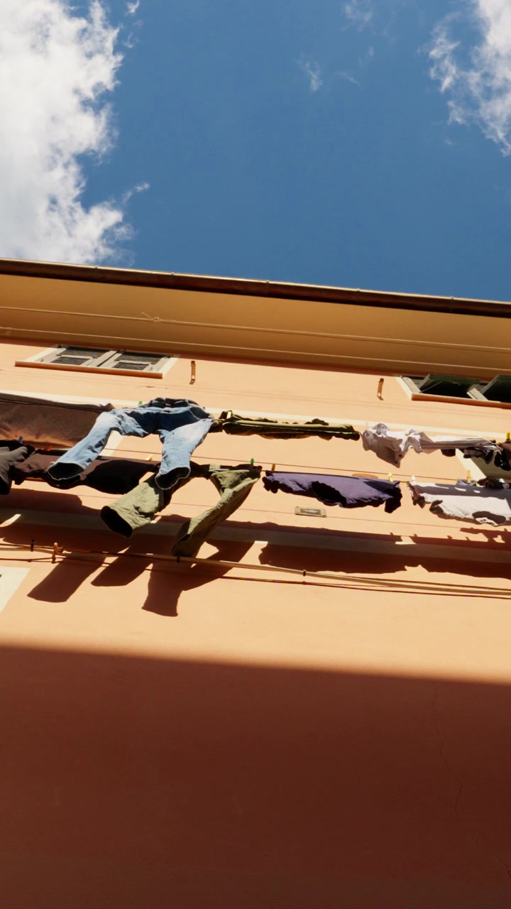 Low angle vertical shot of laundry hanging between windows on colorful building in Vernazza Cinque Terre