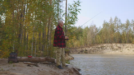 human-is-relaxing-at-nature-enjoying-angling-and-spin-fishing-in-wild-forest-river-standing-alone-on-shore-holding-rod