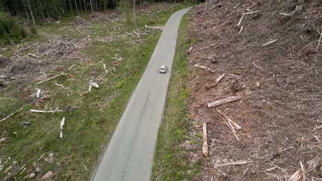 siguiendo alto detrás de un todoterreno blanco que viaja a través de un área forestal talada, seguimiento aéreo