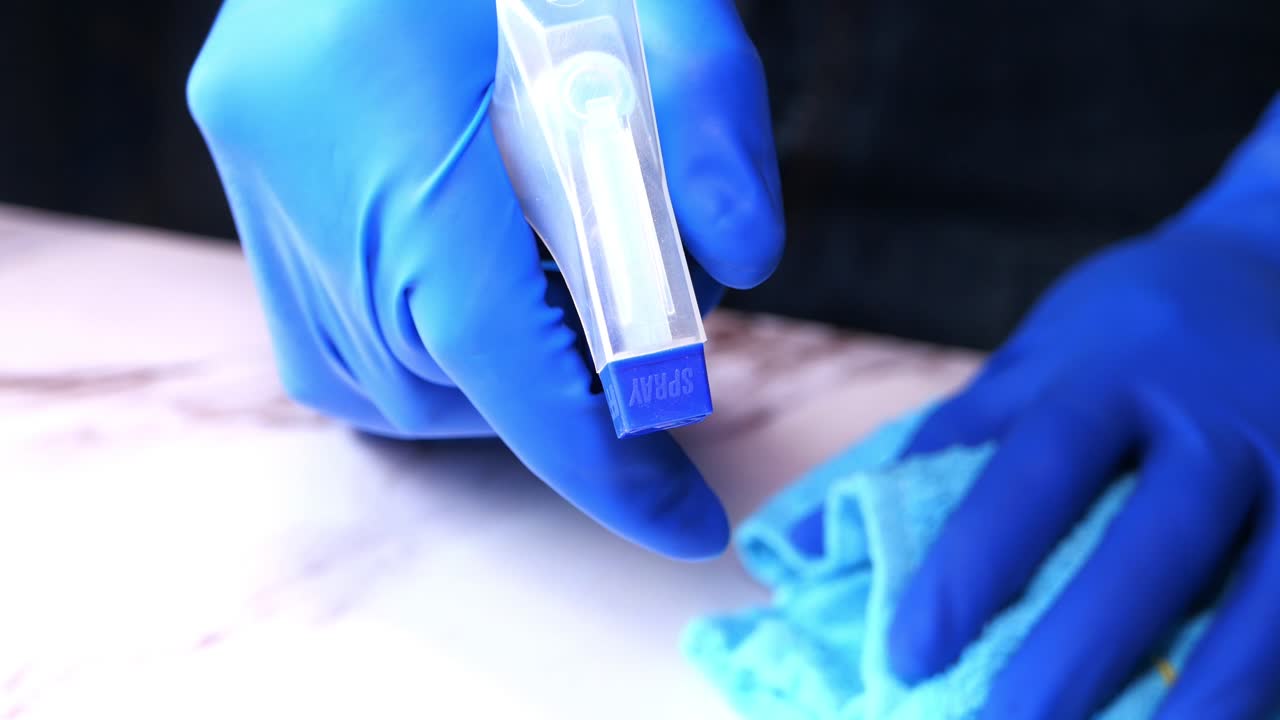 limpieza de una encimera de mármol con una botella de pulverización y un paño