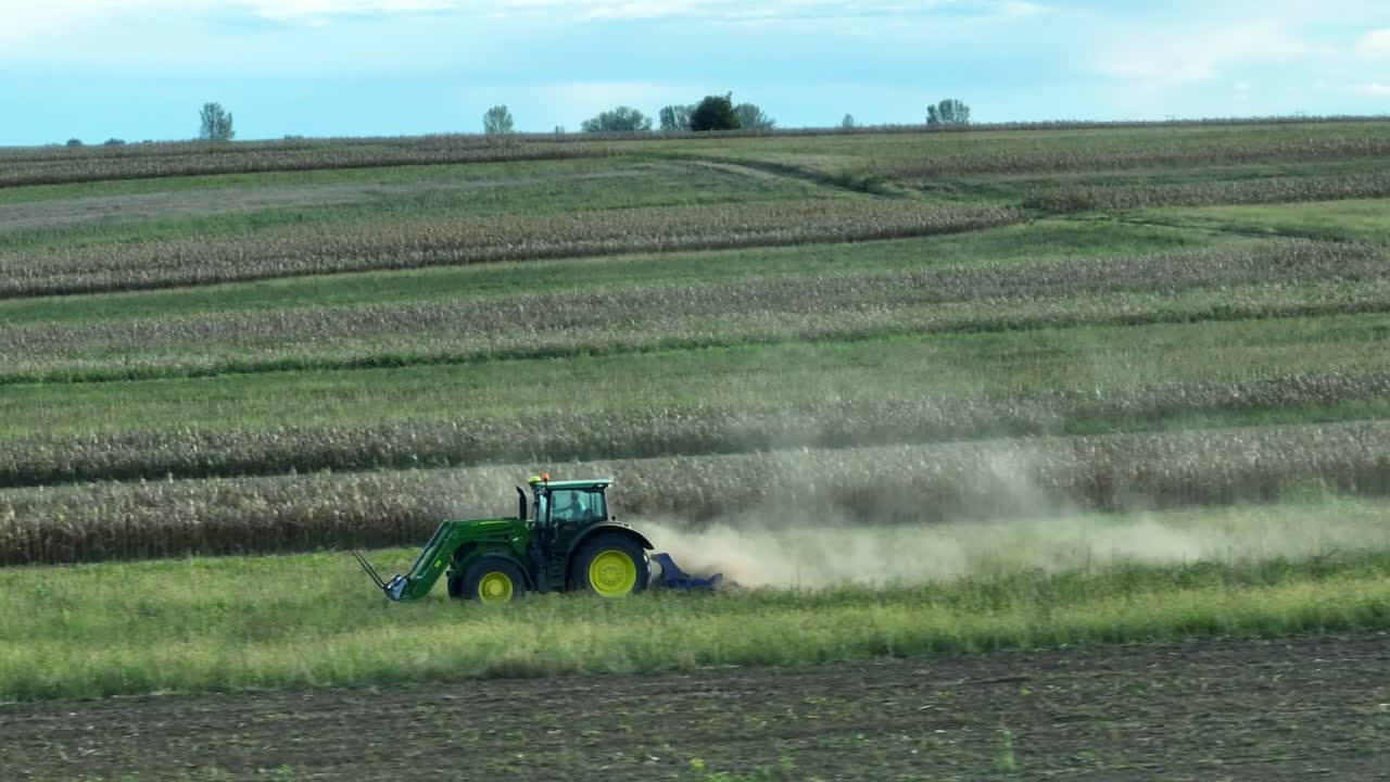 Ripresa aerea in movimento di un trattore industriale che lavora su un campo agricolo durante una giornata di sole - polvere che vola nell'aria
