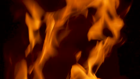 close up of fire flames burning wood logs in slow motion reaching hot temperature and creating abstract patterns on black background for easy compositing 4k