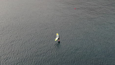 Drohnenaufnahme-Eines-Mannes,-Der-Im-Meer-Windsurft