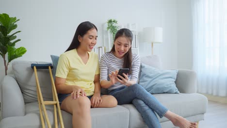 two women friends using smartphone on couch