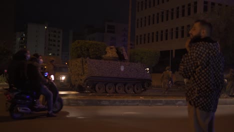 a soldier tank and some soldiers can be seen passing by the road while civilians watch over during a military operation in tripoli, lebanon