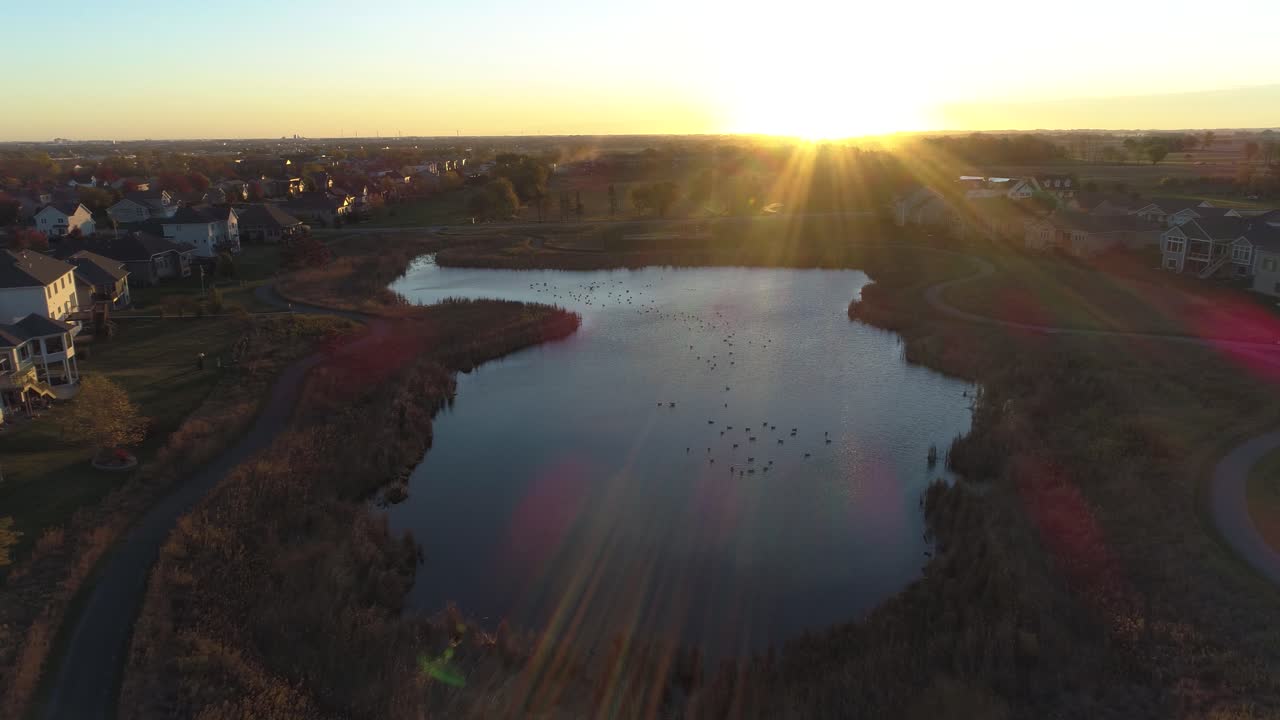 주택가 사이에 있는 일출 때 연못을 향해 천천히 내려갑니다.