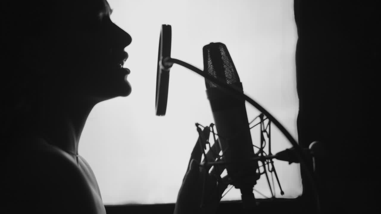 Woman singing in the recording studio. Profile of a woman with a beautiful face and lips. Black and White