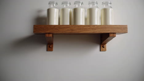 five milk bottles on a wooden shelf