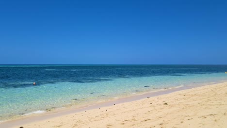 slow aerial low flying over sandy beach on green island with pan left view of ocean