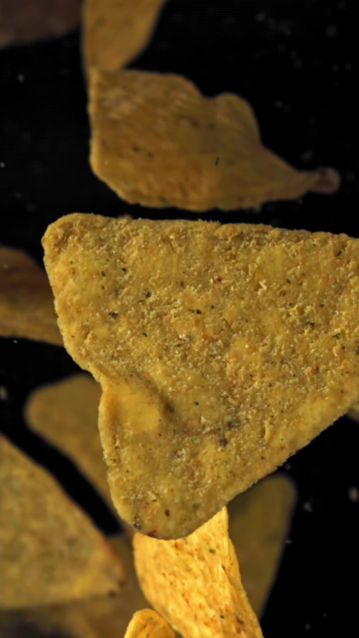 Fallande tortillachips med kryddning i slow motion på svart bakgrund