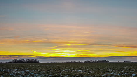 lapso de tiempo del amanecer sobre el campo de cultivo de cultivos cosechados en otoño o invierno con algo de nieve en el suelo