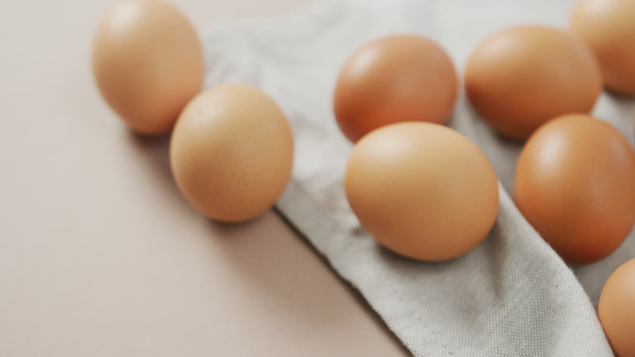 Video of close up of eggs and on rustic cloth on beige background