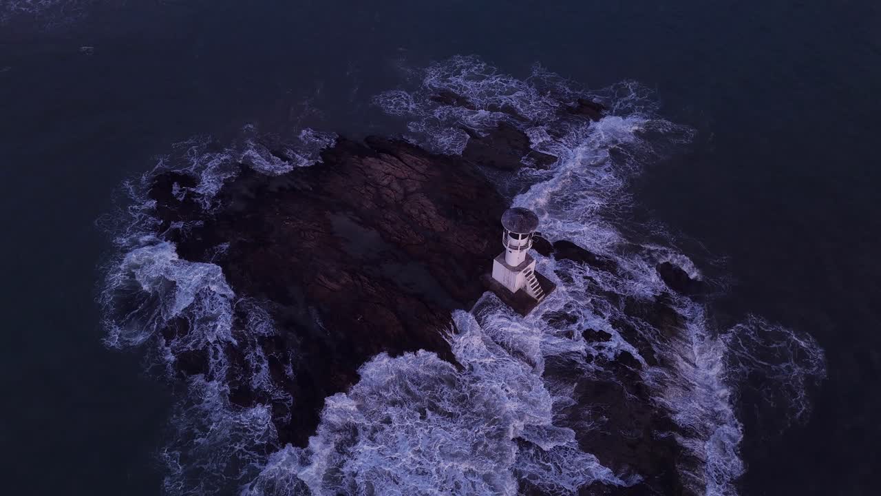 Lighthouse on a rocky island with crashing waves