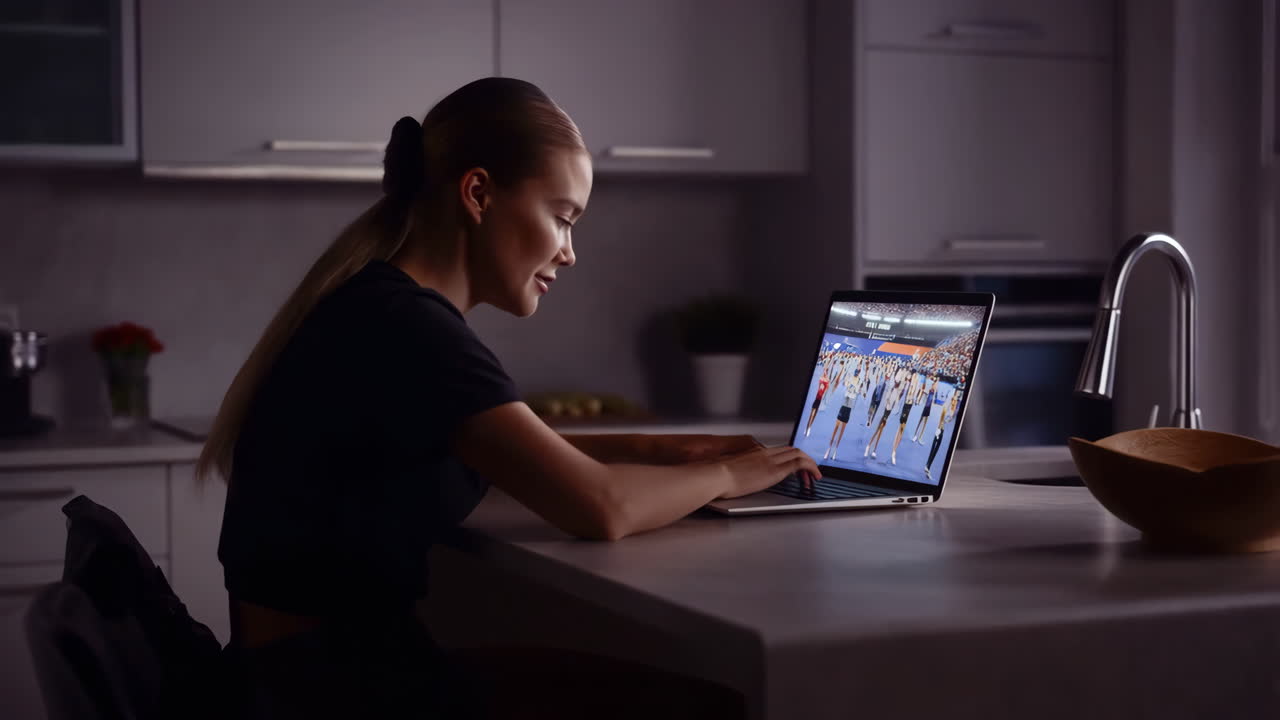 Woman Watching Sports on Laptop in Kitchen