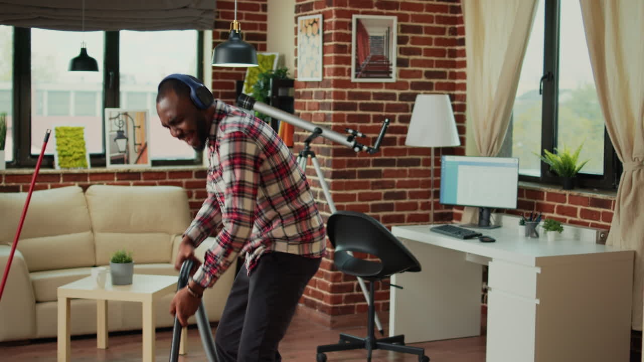 African american man dancing and vacuuming home floors