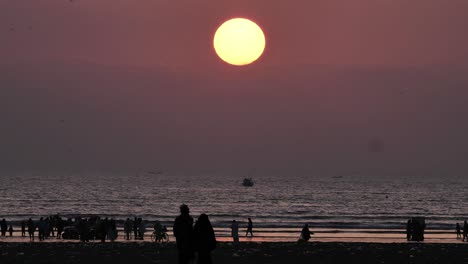 Sol-Amarillo-Con-Puesta-De-Sol-Y-Silueta-De-Personas-En-La-Playa-De-Karachi-Caminando-A-Distancia