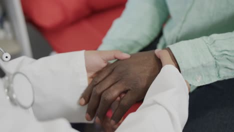 sección media de una doctora diversa examinando a un paciente masculino en la sala de consulta, cámara lenta