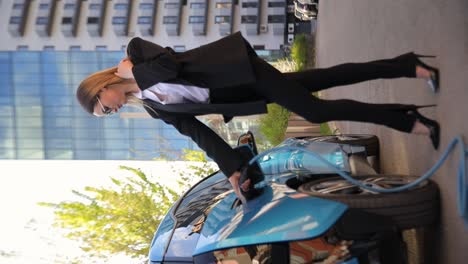 close-up of woman charging electric blue car at station. vertical video