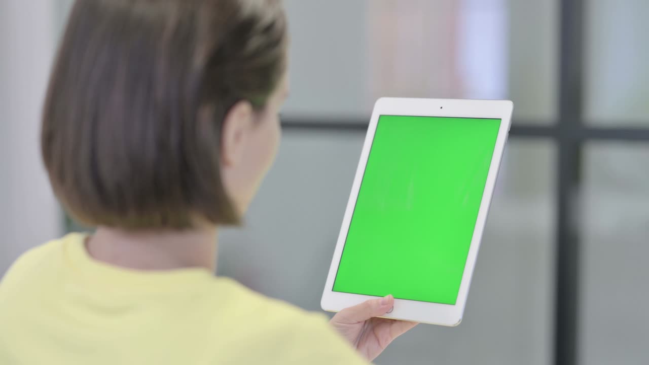 녹색 화면을 가진 태블릿을 사용하는 젊은 여성