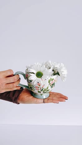 hand holding a decorative mug with flowers