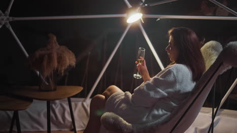 warm light of lamp envelops only alone woman cloaked in comfortable bathrobe. lady immersed in inner world relishing atmosphere of solitary night