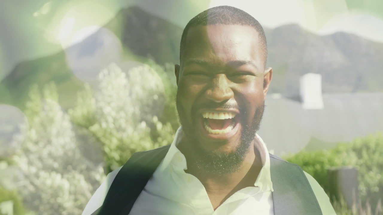 Smiling man outdoors with bokeh light animation over mountains in background