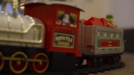 close-up of a miniature train with toy figures passing under a christmas tree