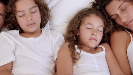 family sleeping on bed together