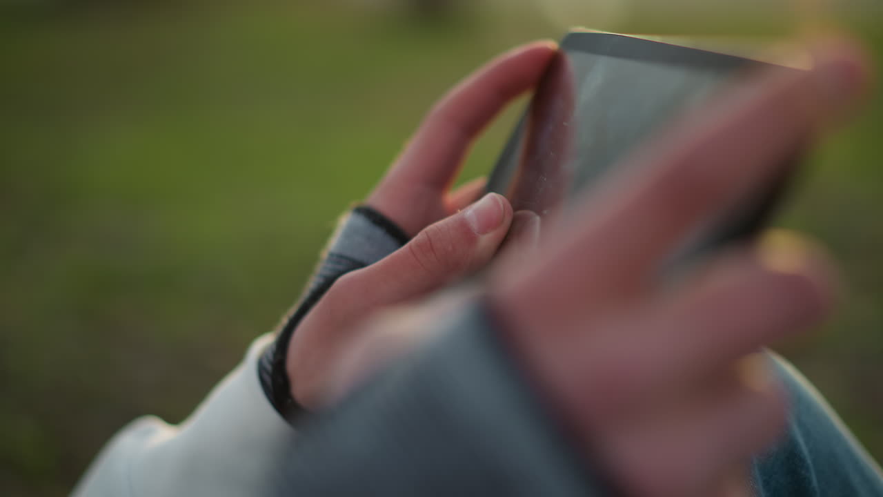 user examining photographs on device with serene green environment background, person leisurely exploring photo collection on tablet surrounded by lush outdoor greenery and natural light influences