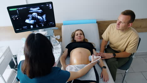 happy future parents in the doctor's cabinet. expecting couple is at ultrasound examination. top view.