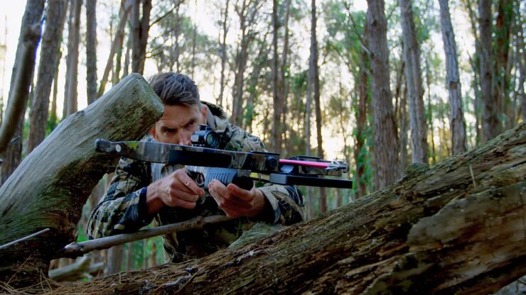 Uomo che mira con un arco compound nel bosco 4k