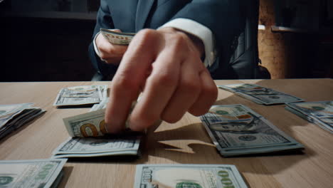 hands collecting dollars piles at desk closeup. business man counting banknotes.