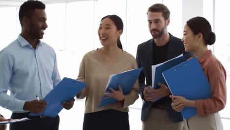 a dynamic group discussion among professionals sharing ideas and insights in a bright, modern office environment with blue folders in their hands