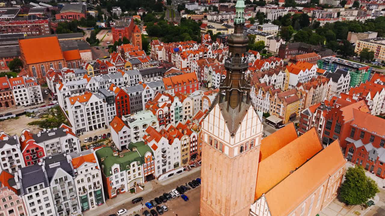 Filmisk, overskyet udsigt over røde hustage og Sankt Nikolaj Kirke i Elbląg