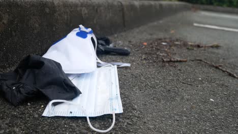 Dirty-discarded-used-corona-virus-masks-and-gloves-garbage-on-sidewalk-blowing-in-wind-with-copy-space