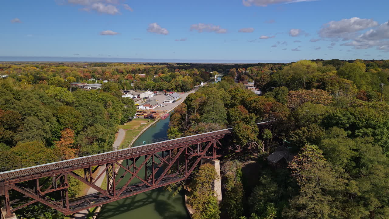 Veduta aerea del ponte ferroviario sul Canale Erie a Lockport, New York, USA, circondato da alberi autunnali e cielo blu.