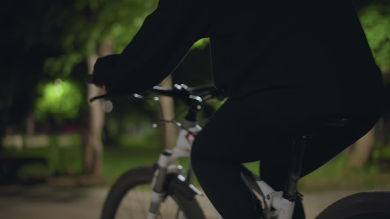 Night Cycle Silhouette, Rider And Bike At Dusk, Silhouette Of Cyclist With Illuminated Trees Behind, Nighttime Picture Showing Rider On Bicycle With Soft Trees Illuminated In Background