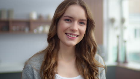 portrait of smiling woman looking camera in kitchen. girl standing in house.