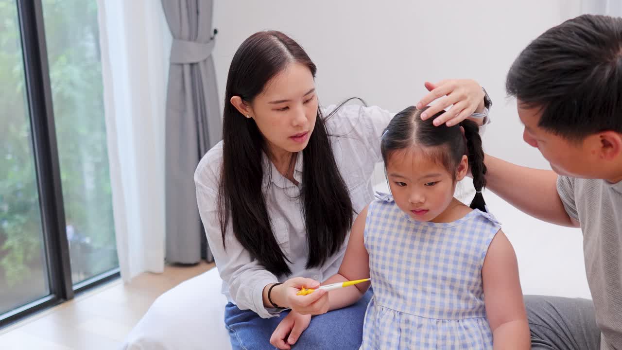 Mother and father check young daughter’s temperature, comforting her in bright, softly lit bedroom