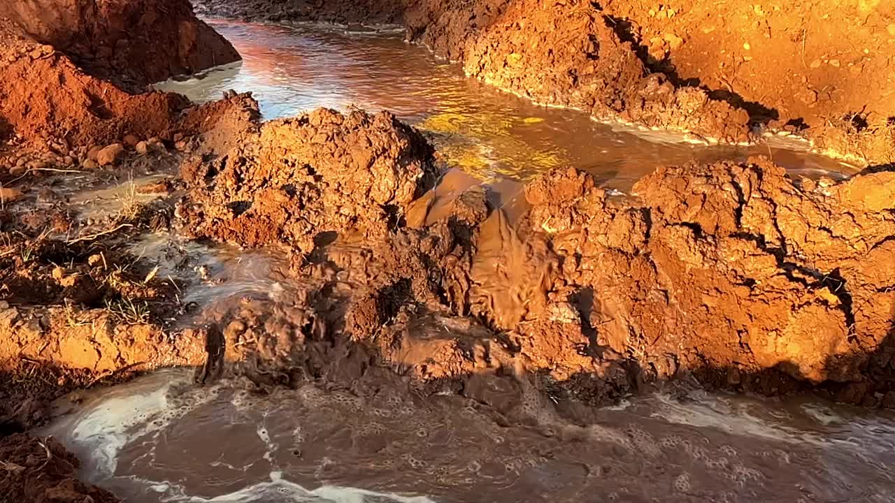 Acqua fangosa che scorre sulla terra in un progetto di costruzione, mostrando la necessità di controllo dell'erosione - al rallentatore